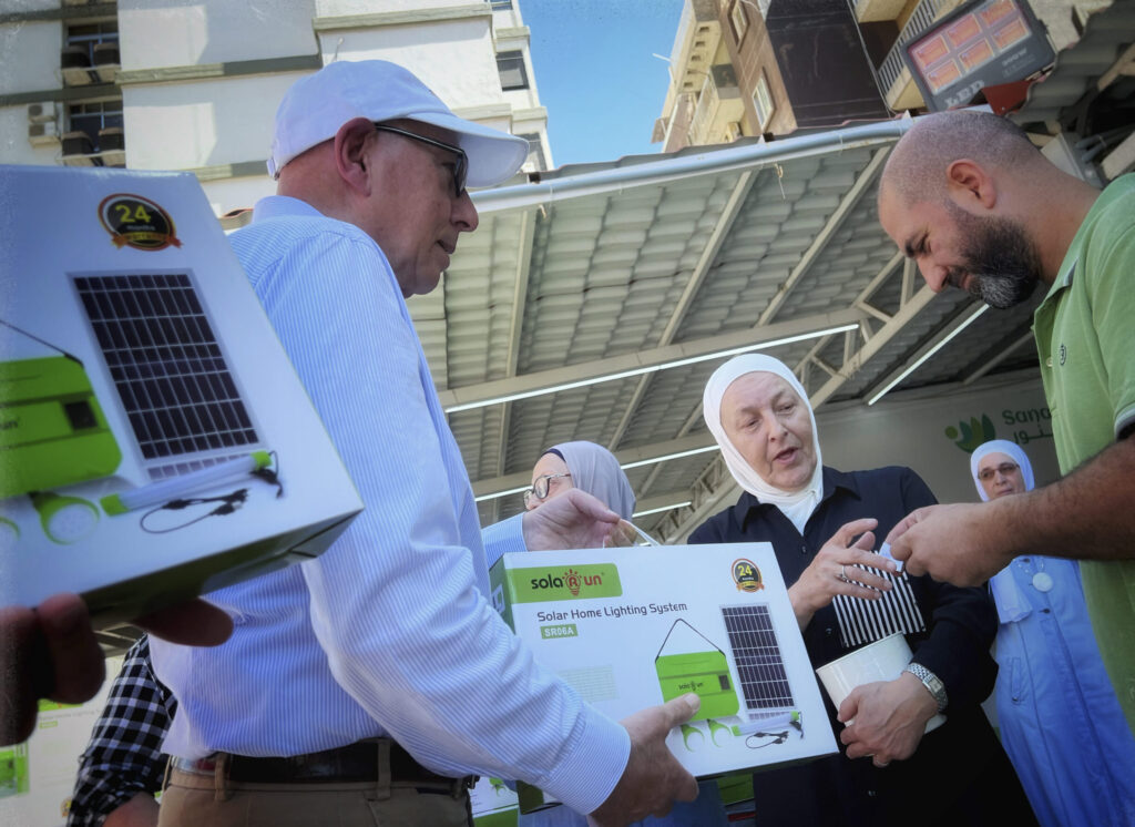 Abdul-Rahman Adib handing out a solar lamp set to one benificary