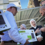 Abdul-Rahman Adib handing out a solar lamp set to one benificary