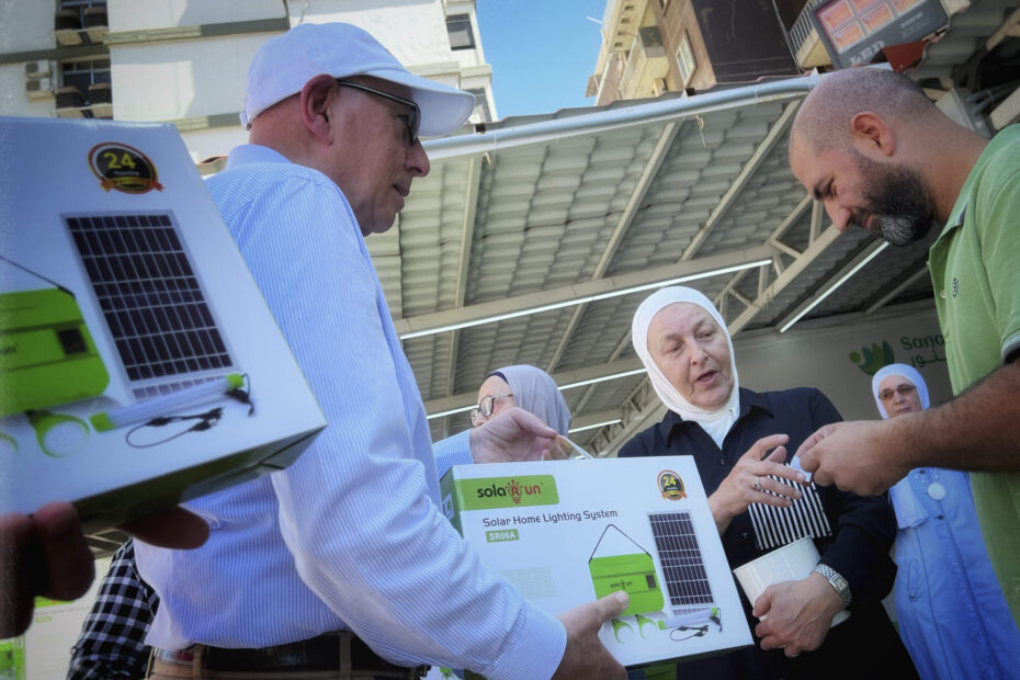 Abdul-Rahman Adib handing out a solar lamp set to one benificary